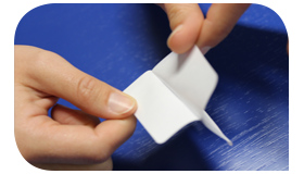 Zwei Hände, die ein Etikett teilweise vom Trägerpapier auf einem blauen Hintergrund abziehen.