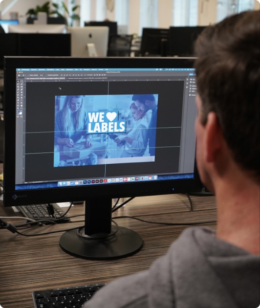 Man from behind, viewing label designs on a monitor.