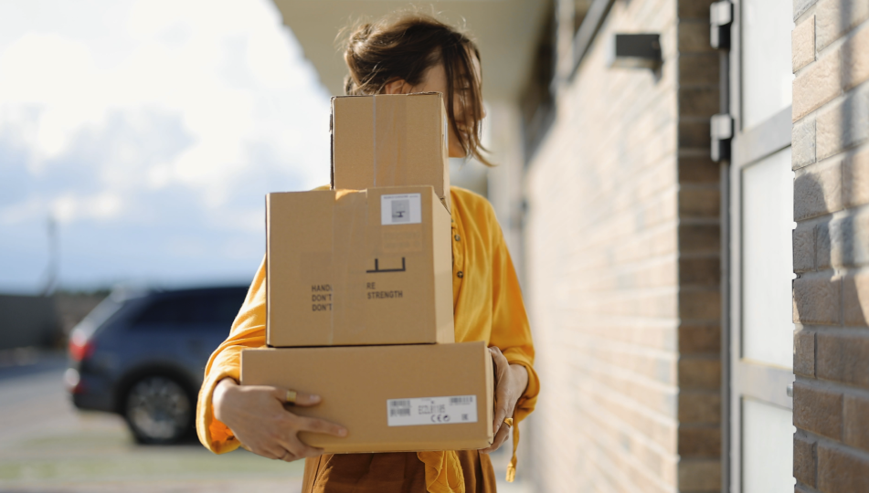 Photo d'une femme livrant des boîtes emballées à une maison avec une allée effacée en arrière-plan.