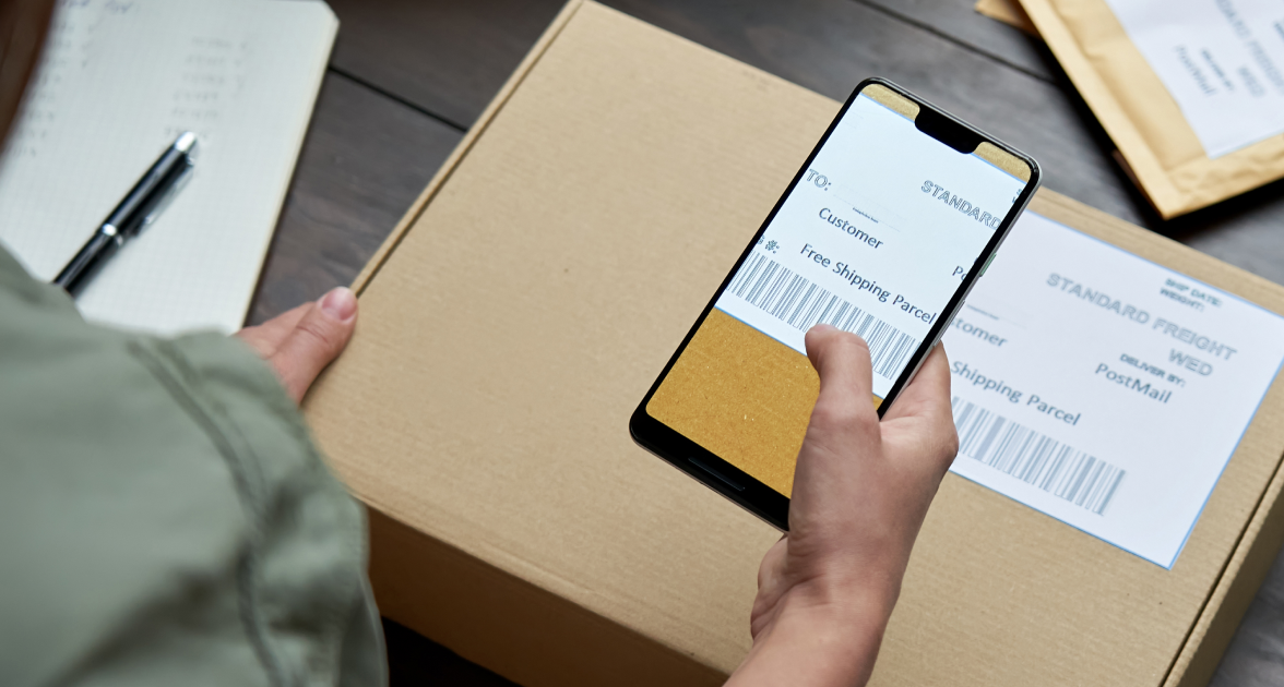 Gros plan d'une main scannant un code-barres sur une boîte emballée.