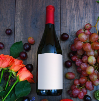 Dark glass wine bottle with a white label, lying on a wooden background with a rose on the left and grapes on the right.